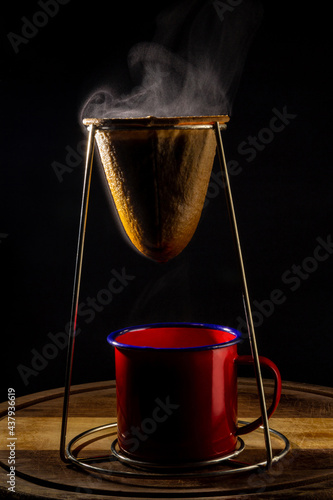 Café sendo coado e derramado diretamente na caneca vermelha. Com vapor subindo. photo