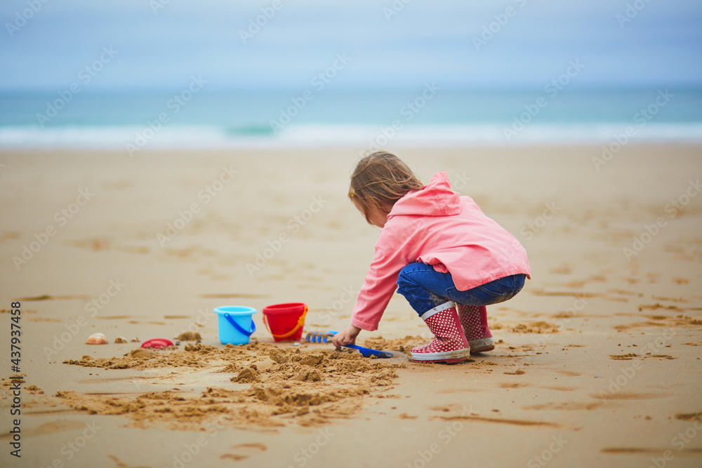 Adorable toddler girl playing on the sand beach at Atlantic coast Adorable toddler girl playing on the sand beach at Atlantic coast
