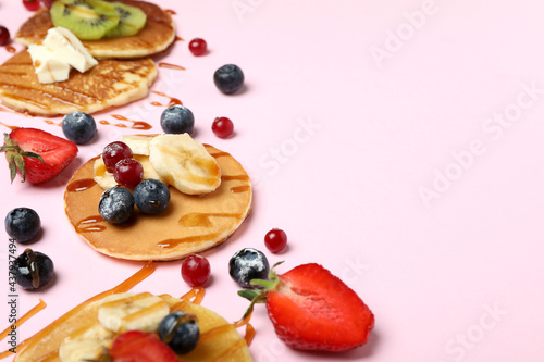 Concept of delicious dessert with pancakes on pink background