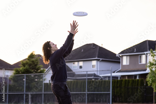 White Caucasian Adult Woman Playing Ultimate Frisbee in the Green Field at neighborhood city park. Surrey, Vancouver, British Columbia, Canada. photo