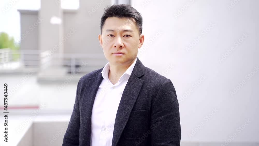 portrait confident asian business man looking seriously at camera on urban background of modern outdoors office building. happy Male businessman in formal black suit and white shirt laughs Smile portrait confident asian business man looking seriously at camera on urban background of modern outdoors office building. happy Male businessman in formal black suit and white shirt laughs Smile