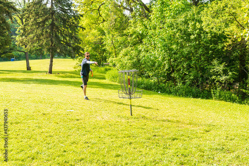 Disc golf is a flying disc sport in which players throw a disc at a target; it is played using rules similar to golf, this player is “putting” on a course in Toronto.