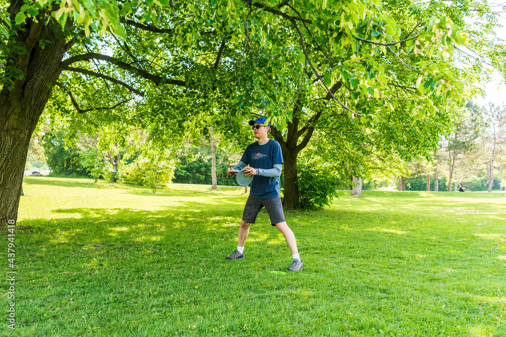Disc golf is a flying disc sport in which players throw a disc at a target; it is played using rules similar to golf, this player is enjoying a early summer morning on a course in Toronto. Disc golf is a flying disc sport in which players throw a disc at a target; it is played using rules similar to golf, this player is enjoying a early summer morning on a course in Toronto.