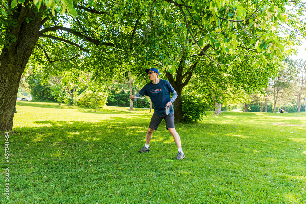 Disc golf is a flying disc sport in which players throw a disc at a target; it is played using rules similar to golf, this player is enjoying a early summer morning on a course in Toronto. Disc golf is a flying disc sport in which players throw a disc at a target; it is played using rules similar to golf, this player is enjoying a early summer morning on a course in Toronto.