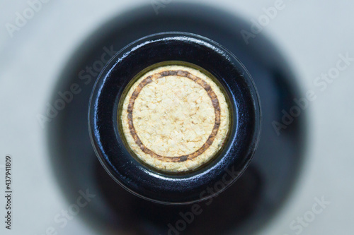 Close-up view of the top of a wine bottle. The bottle is closed with a cork. Traffic jam in focus. The background is blurred. The cork has a round, empty frame. 