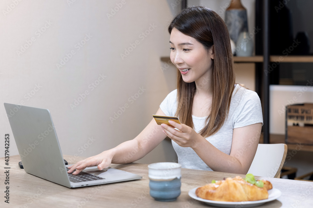 Happy Asian woman shopping online with laptop computer and paying with credit card. Happy Asian woman shopping online with laptop computer and paying with credit card.