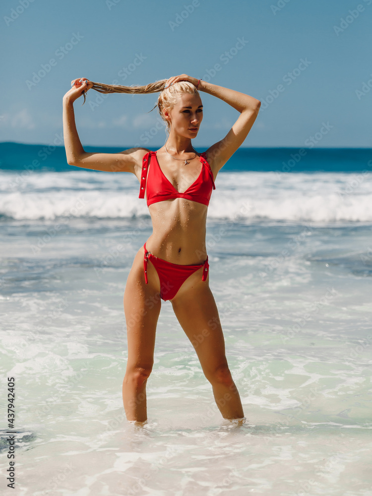 Attractive blonde woman in red bikini at sea beach in Australia