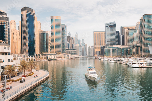 The boat sails along the canal in the Dubai Marina area against the backdrop of numerous residential skyscrapers and hotels