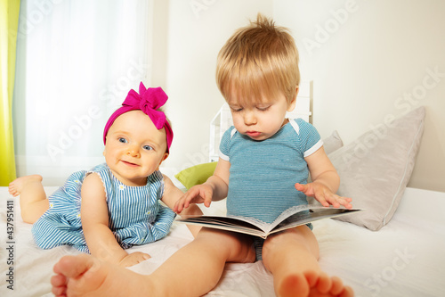 Two little baby kids look and read book together © Sergey Novikov