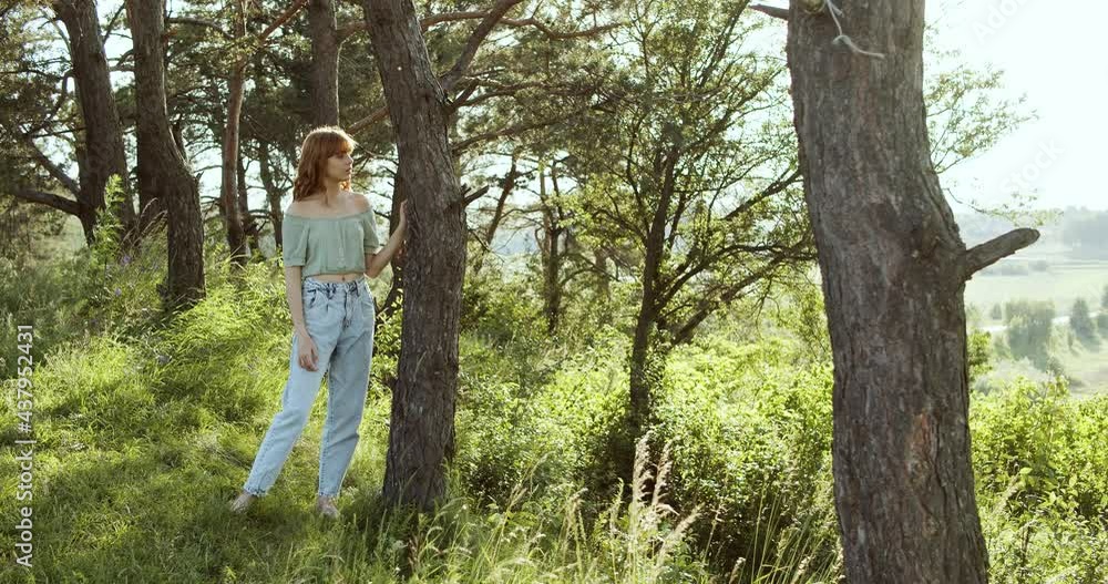 Attractive European chestnut teen girl has a pleasure of nature near a tree in forest on a sunny day. Attractive European chestnut teen girl has a pleasure of nature near a tree in forest on a sunny day.