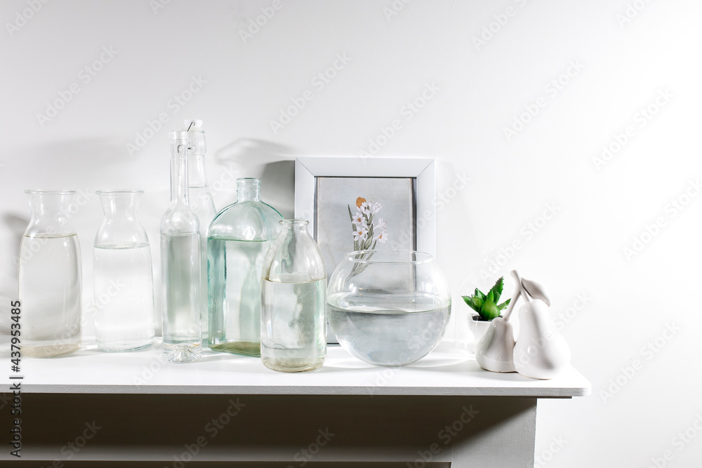 A set of water bottles of different shapes with a photo frame and a pot with artificial succulent is on the dresser A set of water bottles of different shapes with a photo frame and a pot with artificial succulent is on the dresser