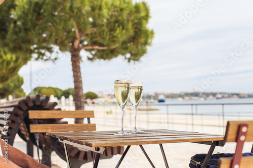 Two glasses of sparkling wine on a wooden table outside with a sea view © Надежда Филатова