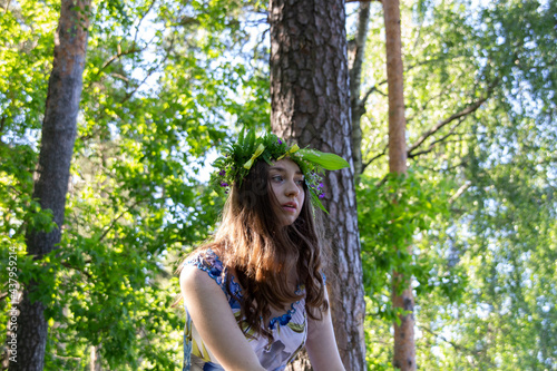 Beautiful blue eye girl in floral crown and dress in the sunnt sumer forest on river side