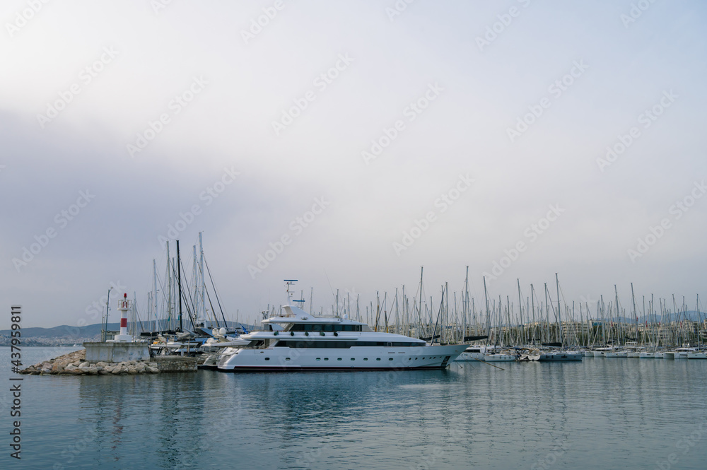 Fototapeta premium Yacht and boats parking in harbor. White sailing yachts at the pier. Sea yacht club. Aegean sea. Athens, Greece. Cloudy day.