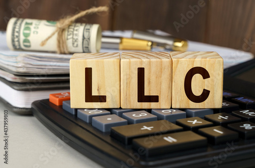 On the table are money, a calculator, a notebook and cubes with the inscription - LLC photo