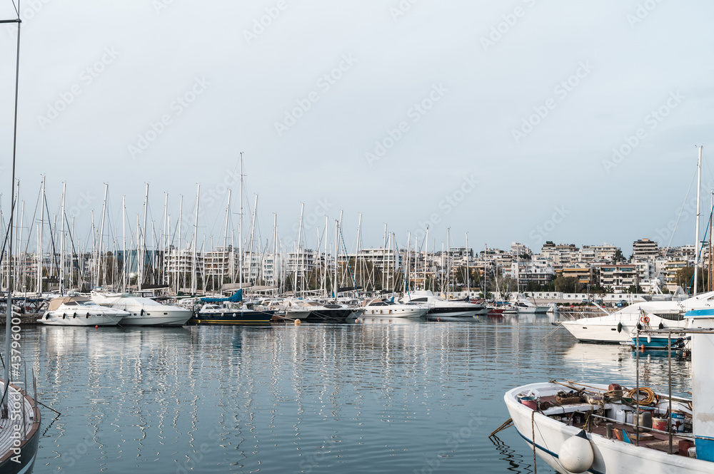 Yacht and boats parking in harbor. White sailing yachts at the pier. Sea yacht club. Aegean sea. Athens, Greece. Cloudy day.