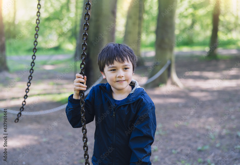 Active kid holding metal chains in playground, Child enjoying outdoors activity in a climbing rope chains in adventure park on sunny day summer, Cute young boy having fun on a public playground Active kid holding metal chains in playground, Child enjoying outdoors activity in a climbing rope chains in adventure park on sunny day summer, Cute young boy having fun on a public playground