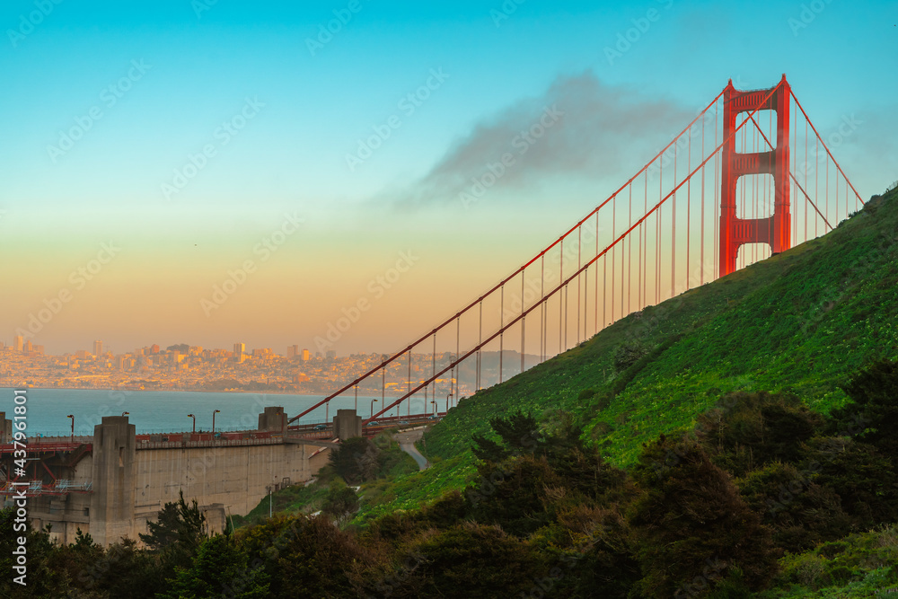 Obraz premium The top of the Red Golden Gate Bridge in the clouds photographed from a hill at sunset, San Francisco