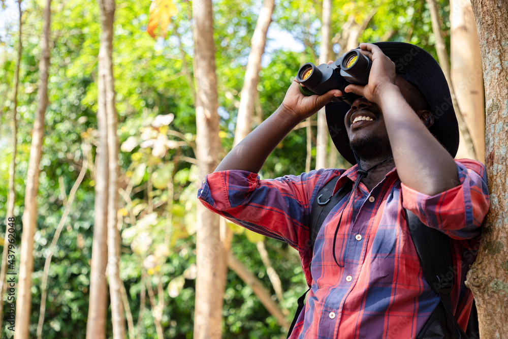 Happy Africa American hipster man backpack using binocular for search animal in nature public park and find location for camping, Relax time on holiday concept travel. Travel and Hiker concept Happy Africa American hipster man backpack using binocular for search animal in nature public park and find location for camping, Relax time on holiday concept travel. Travel and Hiker concept