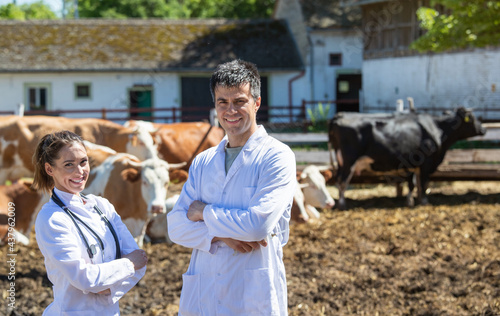Two vets smiling looking at camera with arms crossed on dairy farm.