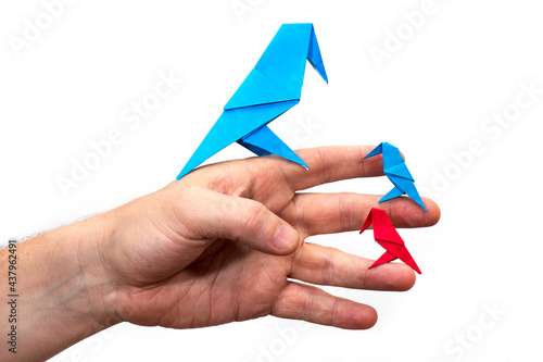 Hand holds an Origami bird made of colored paper isolated on white background