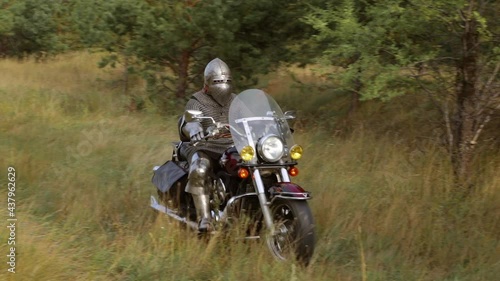 Medieval warrior in full set of armor, chain mail and helmet, rides a motorcycle. Biker knight concept. The rider is in reliable protection.