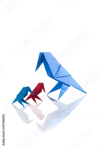 Origami bird made of colored paper isolated on white background. Family concept