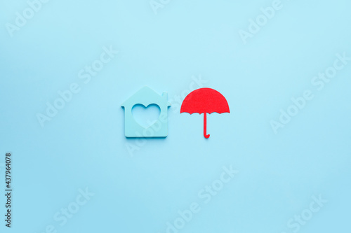 House figure with umbrella on color background. Property insurance concept