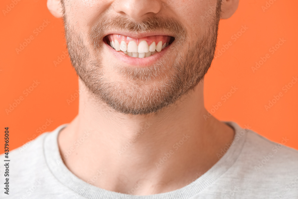 Obraz premium Smiling young man on color background, closeup