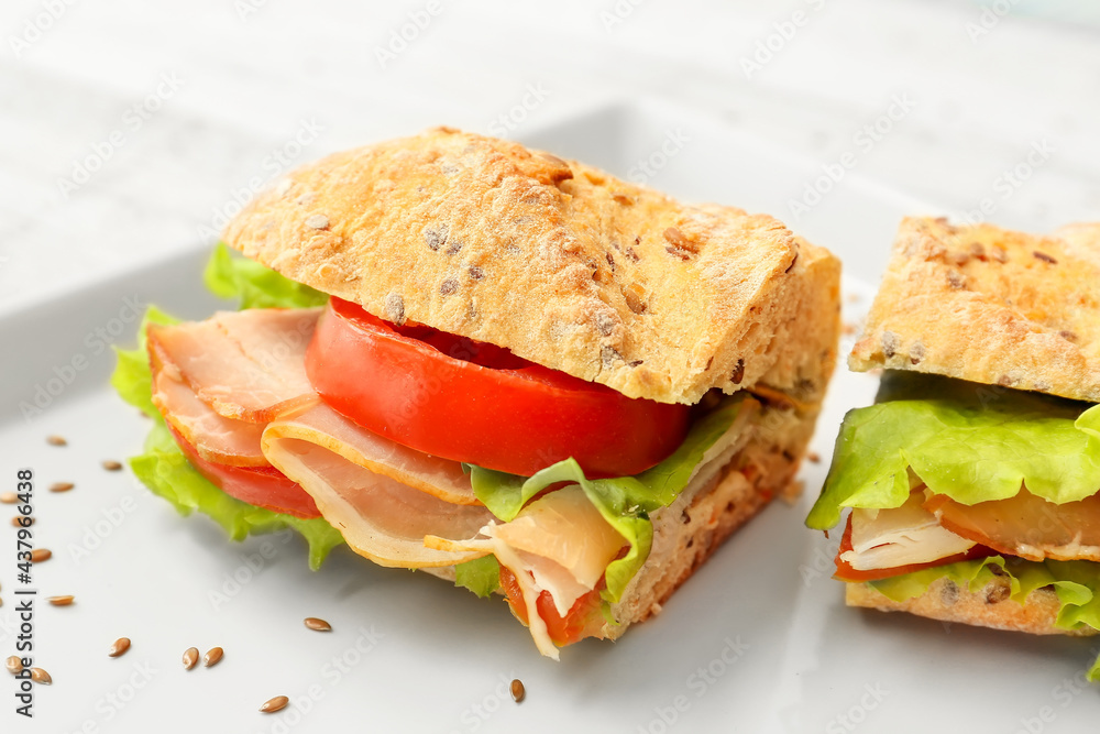 Plate with tasty ciabatta sandwich on light wooden background Plate with tasty ciabatta sandwich on light wooden background
