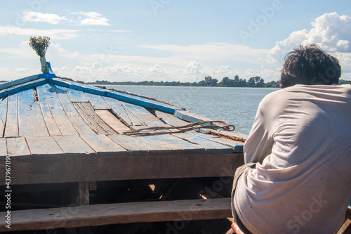 sailor guiding boat accross lake in Myanmar in old blue boat