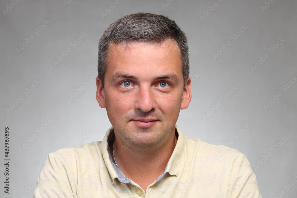 A handsome man in a pastel yellow shirt in the studio looks at the camera. A handsome man in a pastel yellow shirt in the studio looks at the camera.