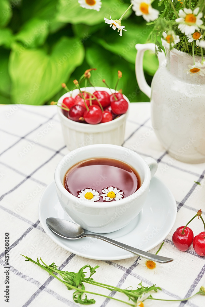 Breakfast outside. Cup of tea, strawberries, cherries, chamomile bunch on table. Summer picnic. Good morning concept Breakfast outside. Cup of tea, strawberries, cherries, chamomile bunch on table. Summer picnic. Good morning concept