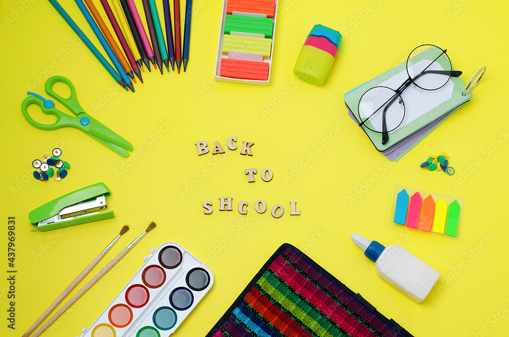 Back to school is written in wooden letters in the middle.School supplies:scissors,stationery buttons,stapler,brushes,paints,notebook,glue,grater,glasses,pencil case,bookmarks,plasticine