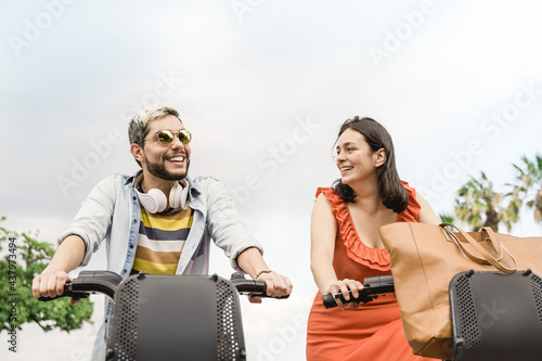 Happy latin couple having fun riding electric bike outdoor at the beach