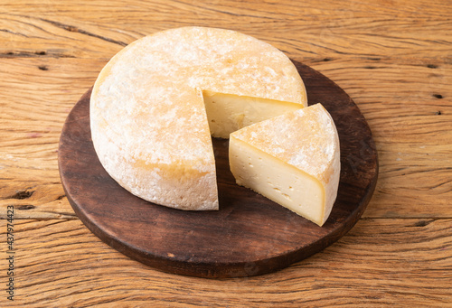 Artisanal Canastra cheese from Minas Gerais, Brazil over wooden board with cut piece photo