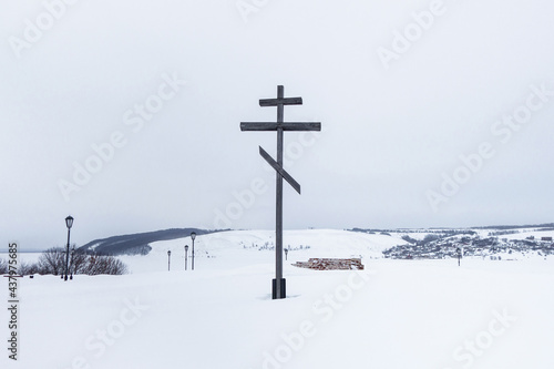 Cross on site of Church of Annunciation of Most Holy Theotokos, destroyed during Soviet era. Ruins can be seen from under snow. Shot in Sviyazhsk, near Kazan, Russia. Snowed river Volga on background
