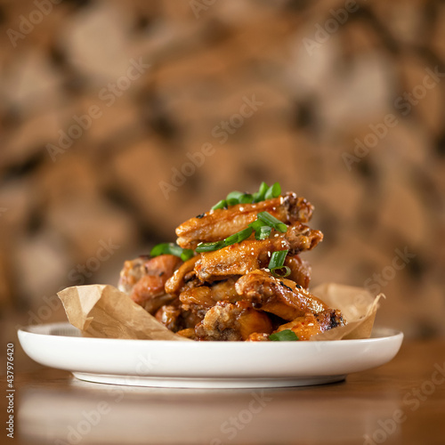 Appetizing roasted or fried chicken wings sesame seeds and onion. Soft focus. Food concept. Square format or 1x1 for posting on social media. Side view. Copy space on top of image.
