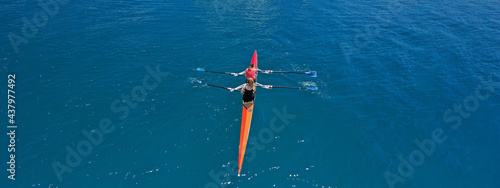 Aerial drone ultra wide photo of fit women athletes rowing in sport canoe in deep blue Aegean sea, Greece