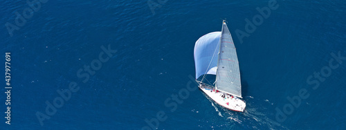 Aerial drone ultra wide panoramic photo of beautiful sail boat with white sails cruising deep blue sea near Mediterranean destination port