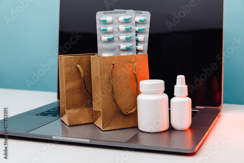 Online pharmacy concept. Paper bags with prescription drugs and pills and white conteiners on laptop photo