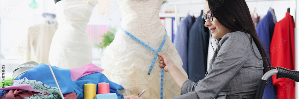 Disabled woman in wheelchair taking measurements from wedding dress Disabled woman in wheelchair taking measurements from wedding dress