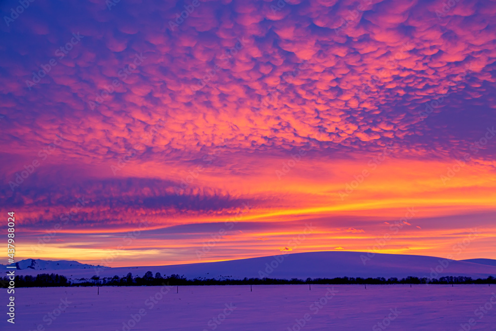 Fototapeta premium Vivid saturated beautiful sunset sky in pink, purple and yellow colors with a mountain. Sunset background.