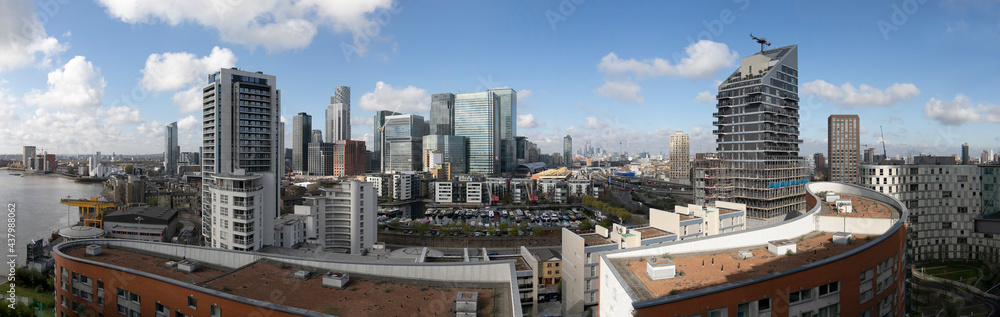 A skyscraper-high view of London's business district, Canary Wharf. in the photo the river thames, canary wharf and skyscrapers appear together against a london background.