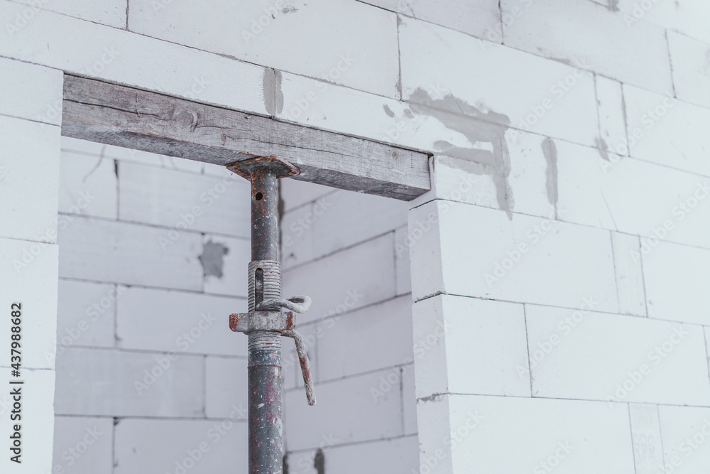 The construction strut supports the cinder block while it solidifies in the doorway