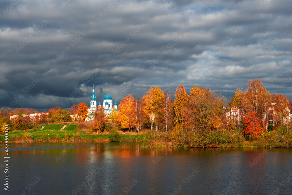 White Cathedral in the distance surrounded by golden autumn trees. Gatchina old city.
