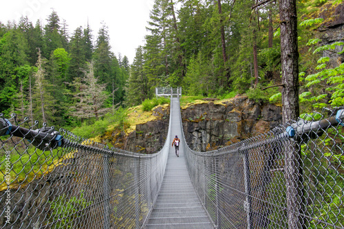 Vancouver Island - Elk Falls Provincial Park suspension bridge. The view on the hiker walking on the bridge above deep canyon.