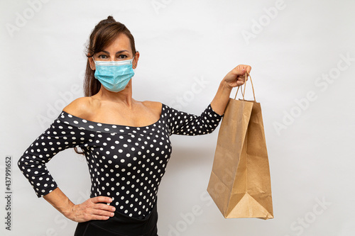 consumidor usando uma máscara protetora mostrando o saco de papel que ela recebeu do entregador photo