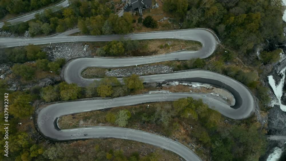 Top aerial drone view on small mountain road with sharp switchback turns. Professional road cyclist ride fast on carbon racing bike. Grand tour race or competition training concept Top aerial drone view on small mountain road with sharp switchback turns. Professional road cyclist ride fast on carbon racing bike. Grand tour race or competition training concept
