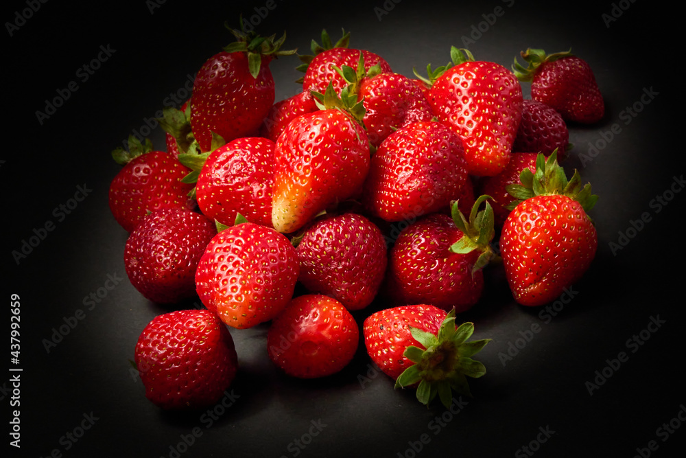 A slide of ripe red strawberries on a black background, close up. A slide of ripe red strawberries on a black background, close up.